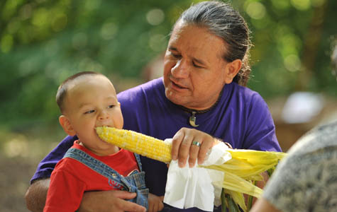 Man feeding young boy corn on the cob