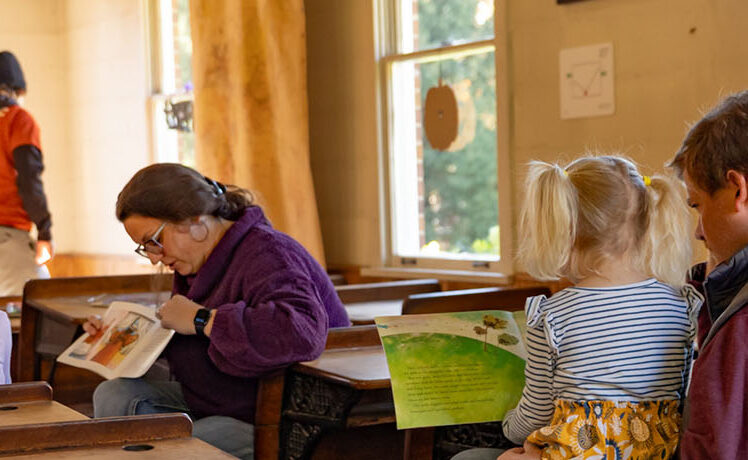 Parents sitting with their children in the Blackberry Farm schoolhouse during Pumpkin Weekends. Season Passes include free admission to Pumpkin Weekends.